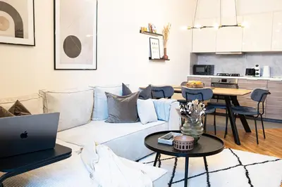 a living room with a couch and a table with a laptop at Rentero Cozy Industrial 8min Dancing House Apartment, Prague in Prague