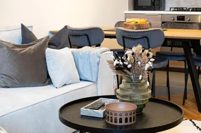 a living room with a couch and a table with flowers at Rentero Cozy Industrial 8min Dancing House Apartment, Prague in Prague