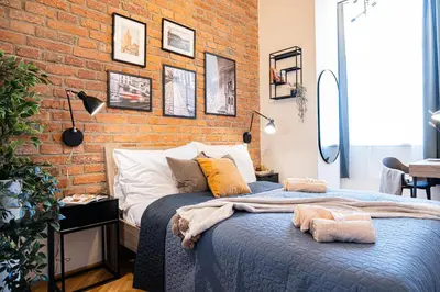 a bedroom with a brick wall and a bed at Rentero Cozy Industrial 8min Dancing House Apartment, Prague in Prague