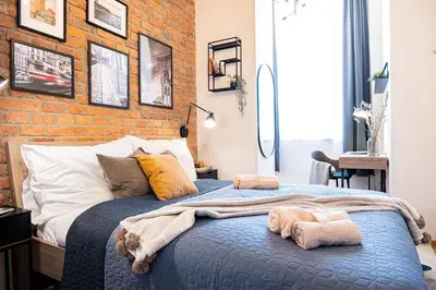 a bedroom with a brick wall and a blue bed at Rentero Cozy Industrial 8min Dancing House Apartment, Prague in Prague