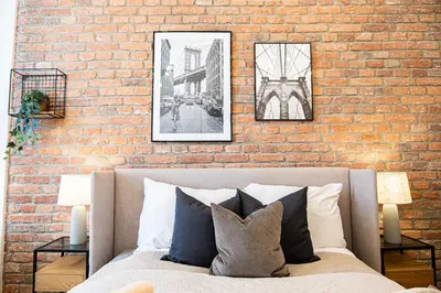 a brick wall with three pictures above a bed at Rentero Cozy Industrial 8min Dancing House Apartment, Prague in Prague