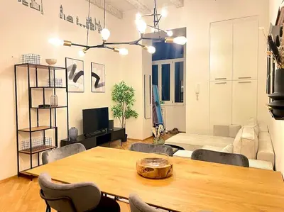 a living room with a table and a bed at Rentero Cozy Industrial 8min Dancing House Apartment, Prague in Prague