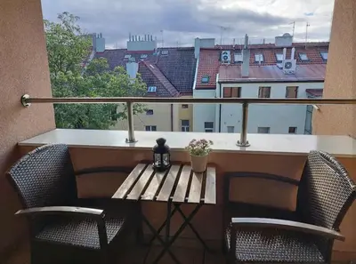 a balcony with a wooden table and chairs and a window at Cozy rooftop with balcony in Prague