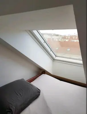 a bed in a room with a window at Cozy rooftop with balcony in Prague