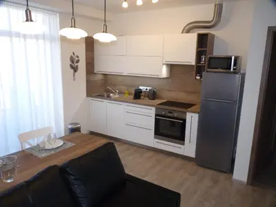 a kitchen with white cabinets and a stainless steel refrigerator at Apartmán Trilobit in Beroun