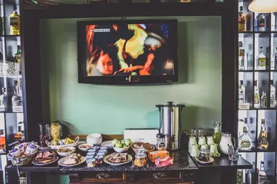 a tv on a wall above a table with food at Penzion Rodos - Café in Prague