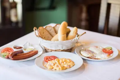a table with plates of breakfast food and a basket of bread at Penzion Rodos - Café in Prague