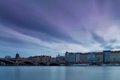 a bridge over the water with buildings and a city at Apartment VLTAVA in Prague