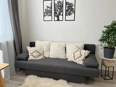 a couch in a living room with two pictures on the wall at Sunny minimalistic flat near metro Opatov in Prague