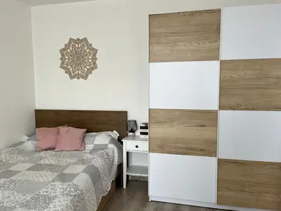 a bedroom with a bed and a desk and a wall at Sunny minimalistic flat near metro Opatov in Prague