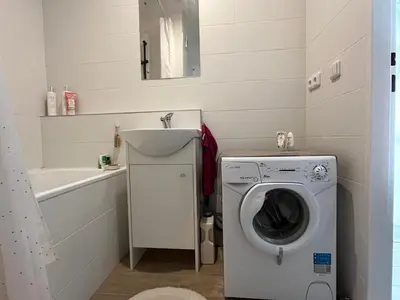 a bathroom with a washing machine and a sink at Sunny minimalistic flat near metro Opatov in Prague
