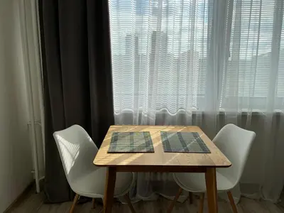 a table with four white chairs and a window at Sunny minimalistic flat near metro Opatov in Prague