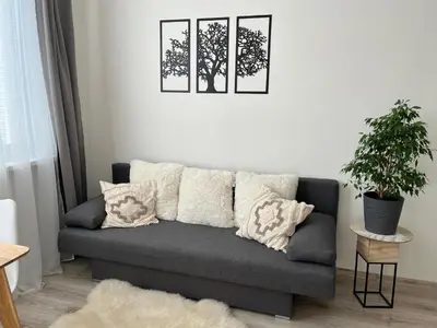 a living room with a gray couch with pillows at Sunny minimalistic flat near metro Opatov in Prague