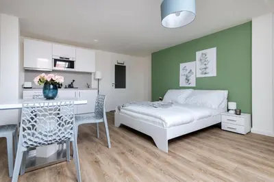 a bedroom with a bed and a table and a kitchen at Central Haven Apartments in Prague