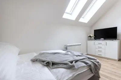 a white bedroom with a bed and a tv at Central Haven Apartments in Prague