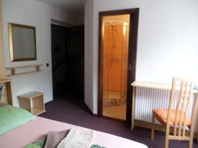 a bedroom with a bed and a chair and a mirror at Penzion v Budech in Křivoklát