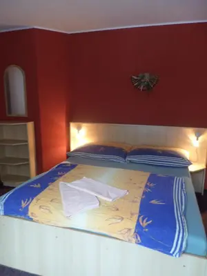 a bed in a room with a red wall at Penzion v Budech in Křivoklát