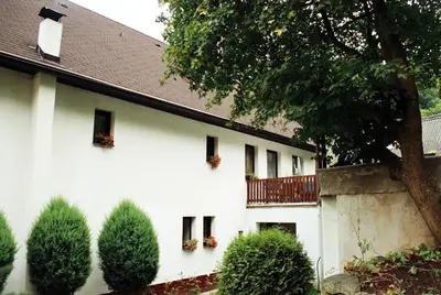 a white building with flowers in the windows at Penzion v Budech in Křivoklát