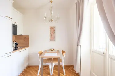 a small white kitchen with a table and a chandelier at Little Chateau in Prague