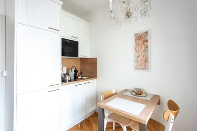 a kitchen with white cabinets and a wooden table at Little Chateau in Prague