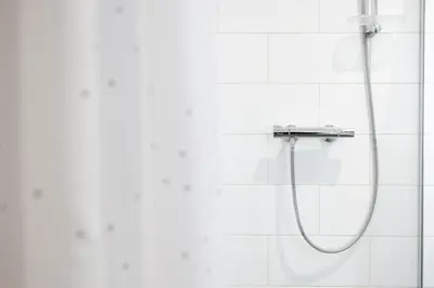 a shower in a white tiled bathroom at U Zlaté hvězdy Kalich in Litoměřice
