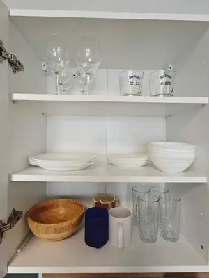 a white shelf with plates and glasses and bowls at Comfort flat with great location in Prague