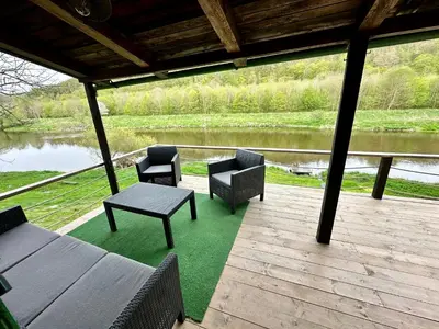 a porch with chairs and a table and a lake at Chata Markétka in Křivoklát