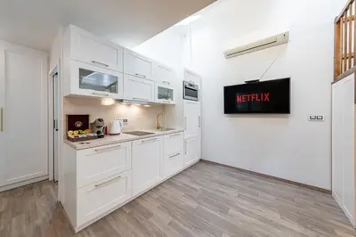 a kitchen with white cabinets and a stainless steel refrigerator at Karlín Boutique Loft Residence by LivingClub in Prague