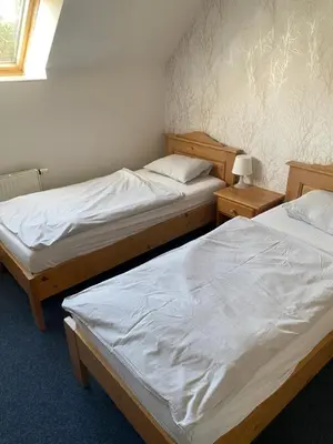 two twin beds in a room with two tables at Penzion BeSeDa in Bratronice