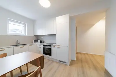 a kitchen with white cabinets and a wooden table at Residence Mozaika in Prague