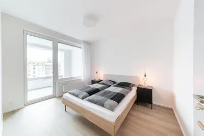 a white bedroom with a bed and a large window at Residence Mozaika in Prague