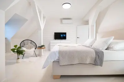 a white bedroom with a bed and a tv at U Zlaté hvězdy Zeibich in Litoměřice