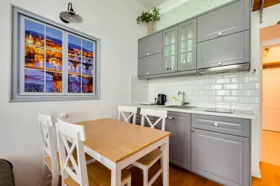 a kitchen with white cabinets and a wooden table at Centrum Bohemia LUX in Prague