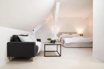 a white bedroom with a bed and a chair at U Zlaté hvězdy Jakub in Litoměřice