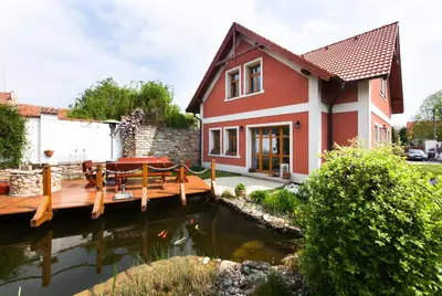 a house with a pond and a wooden deck at Penzion Na Statku in Starý Vestec
