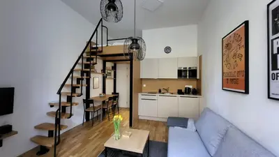a living room with a couch and a table and a kitchen at Endless Jecna in Prague