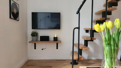 a living room with a television and a vase of yellow flowers at Endless Jecna in Prague