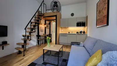 a living room with a blue couch and a kitchen at Endless Jecna in Prague
