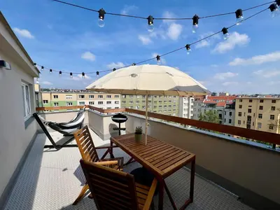 a table and chairs on a balcony with an umbrella at 1 bedroom apartment with terrace and FREE parking near metro in Prague