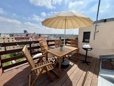 a wooden table and chairs with an umbrella on a balcony at 2 rooms apartment with terrace and FREE parking near metro in Prague
