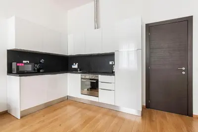 a kitchen with white cabinets and a black door at Riverside Palace Suites in Prague