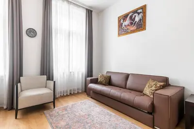 a living room with a brown couch and a chair at Riverside Palace Suites in Prague