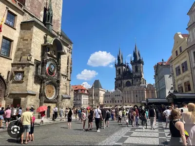 a crowd of people walking around a city with a clock tower at Smichov city Apartments in Prague