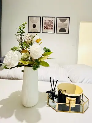 a white vase with flowers on a table in a living room at Cozy Design Homestay right next to Wenceslas Square in Prague