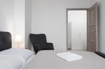 a bedroom with a white bed and a black chair at 2 bedrooms apartment with kitchen near the subway in Prague