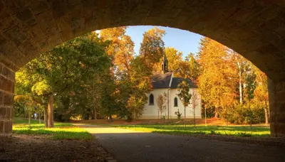 an archway under a bridge with a white church at Penzion Obora in Poděbrady