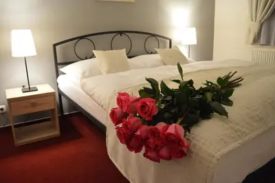 a bed with a bouquet of red roses on it at Penzion Obora in Poděbrady