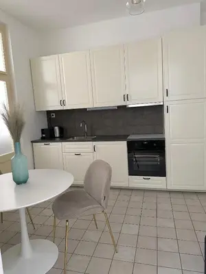 a kitchen with white cabinets and a table and a chair at Útulný byt v centru Prahy in Prague
