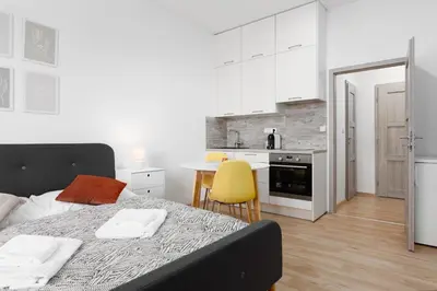 a bedroom with a bed and a kitchen with a table at Quiet apartment with kitchen near the metro in Prague