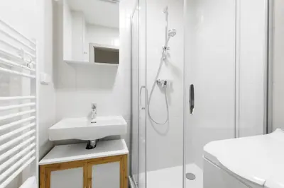 a white bathroom with a sink and a shower at Quiet apartment with kitchen near the metro in Prague
